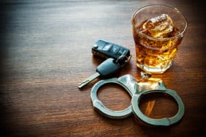 Whiskey, handcuffs, and car keys on a table